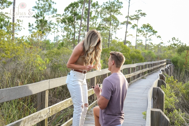 Young man proposing down on one knee to girlfriend on nature trail at Johnsons Beach Perdido Key 