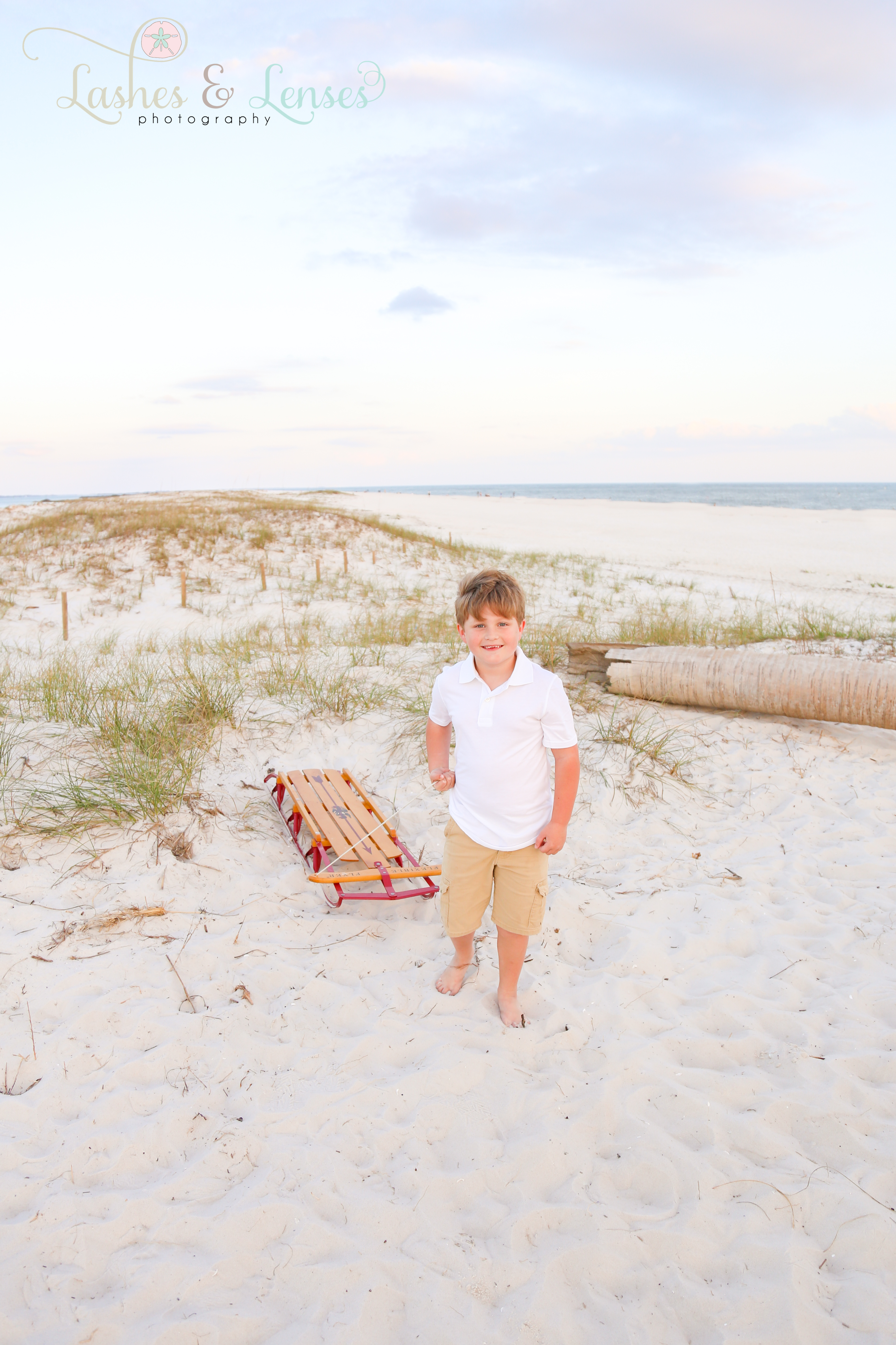 Little boy pulling sled in the sand for Christmas Photos at Johnsons Beach in Perdido Key