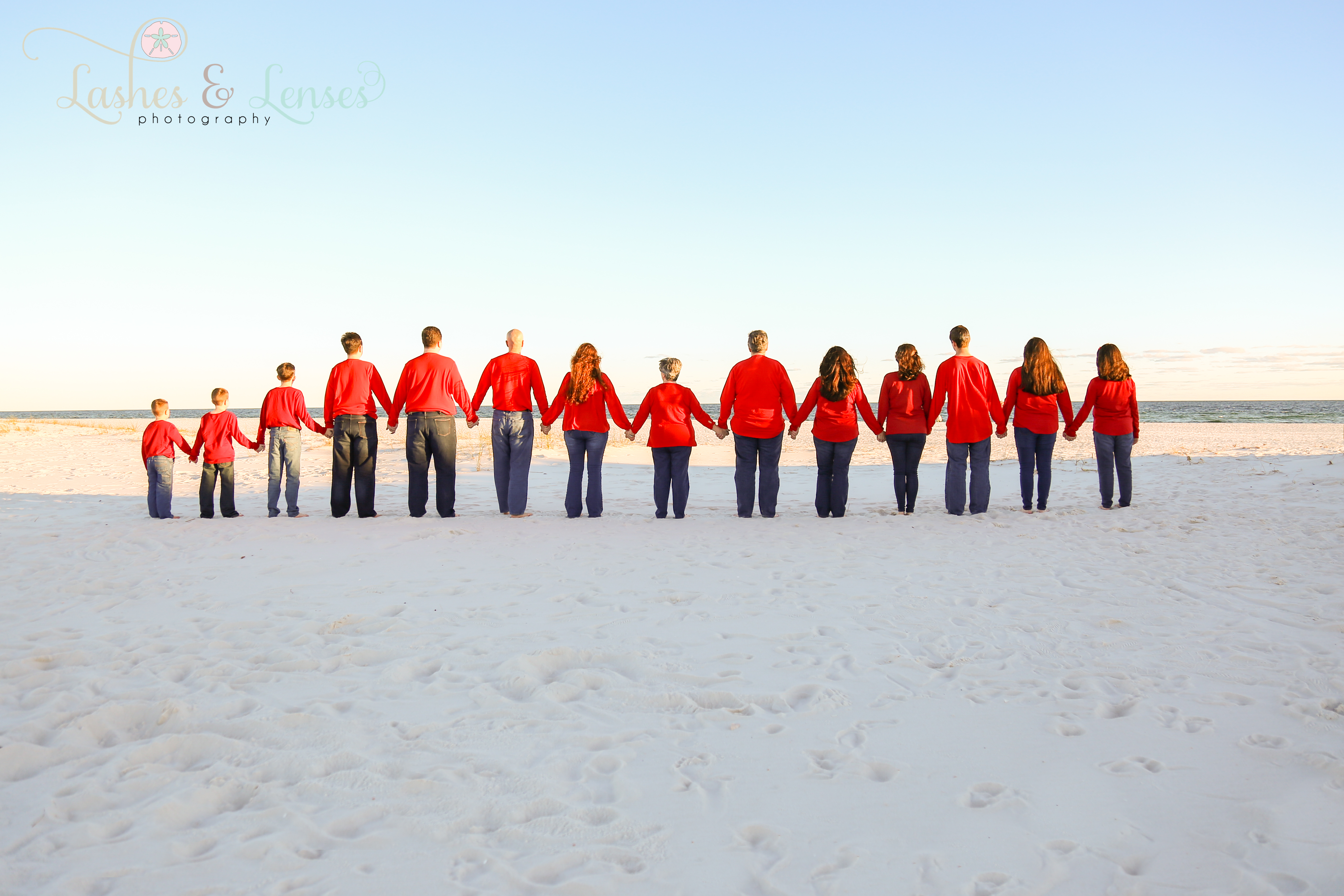 Large extended family standing in a line looking at the water at Johnsons Beach in Perdido Key
