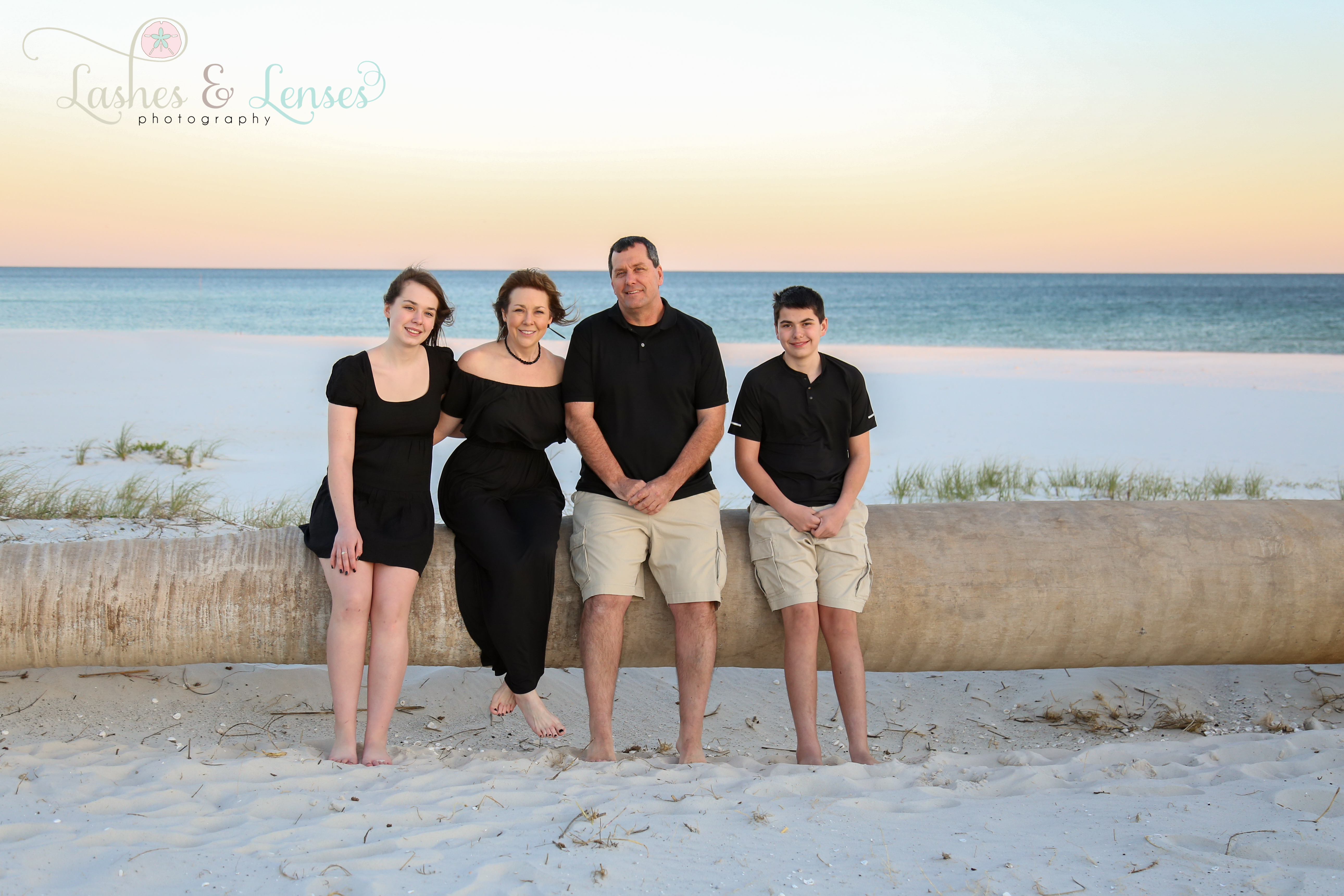 Family sitting on a washed up palm tree on the beach at Johnsons Beach in Perdido Key