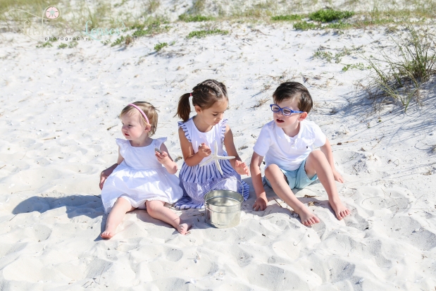 Three young cousins playing in the sand next to the sand dunes at Johnsons Beach in Perdido Key