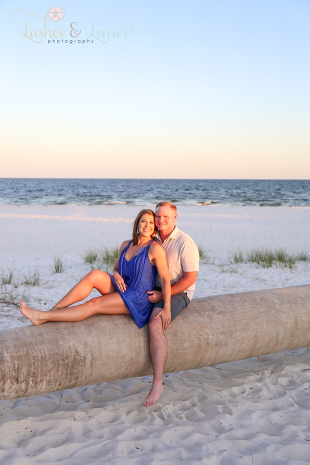 Married Couple sitting on a washed up palm tree with the gulf behind them  at Johnsons Beach in Perdido Key Florida