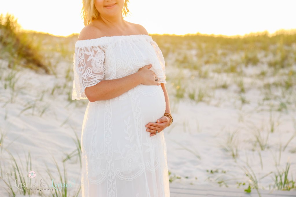 Close up shot of pregnant woman's belly with the sunset behind her at Johnsons Beach in Perdido Key Florida