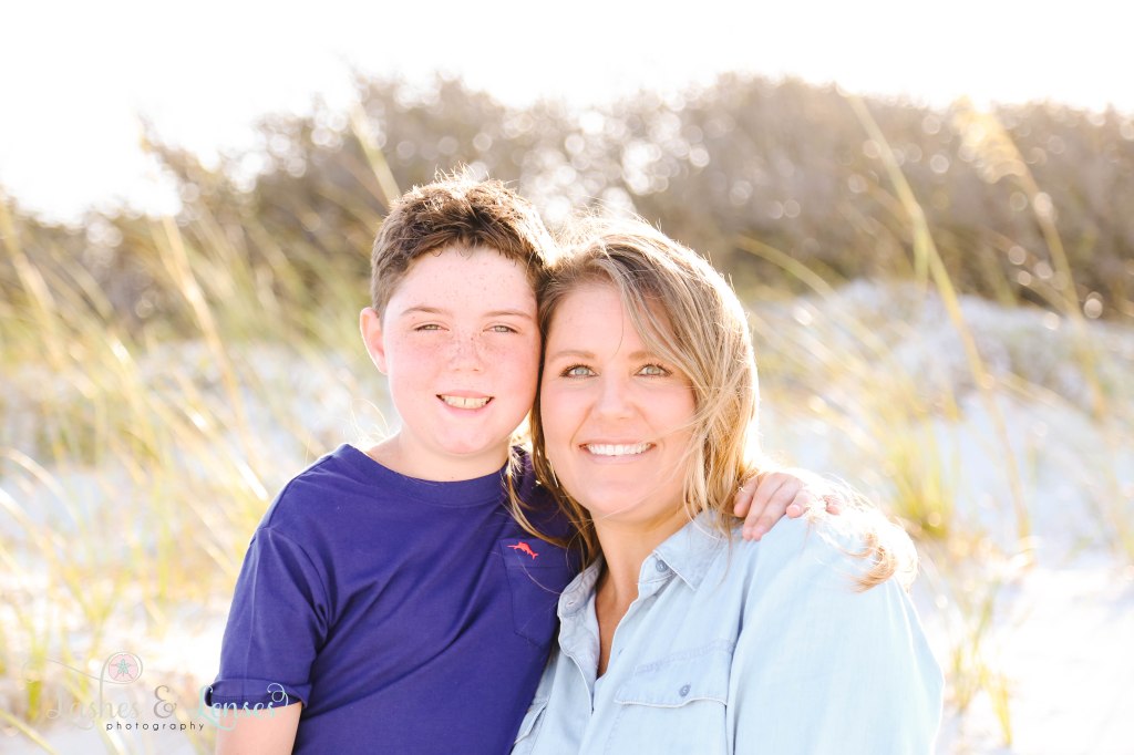 Mom and Son looking right at the camera with the sea oats and bokah behind them at Johnsons Beach in Perdido Key Florida