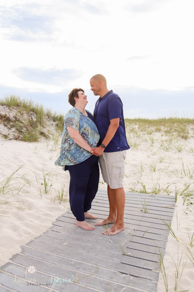 Husband and wife looking into each others eyes and standing on a washed up boardwalk at Johnsons Beach in Perdido Key Florida