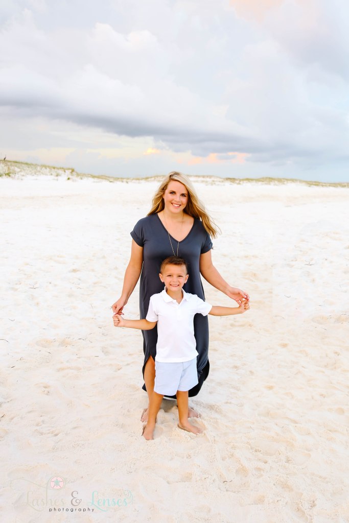 Mom and son standing in the sand with the sand dunes far behind them at Johnsons Beach in Perdido Key Florida