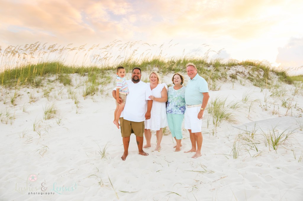 Grandparents, Mom and Dad and son all standing in the sand with the sea oats behind them at Johnsons Beach in Perdido Key Florida