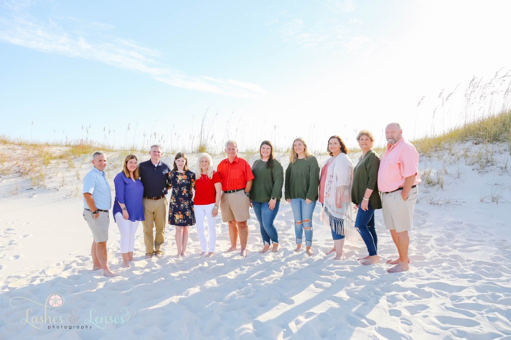 Large extended family standing in the sand with the sand dunes behind them at Johnsons Beach in Perdido Key, Fl