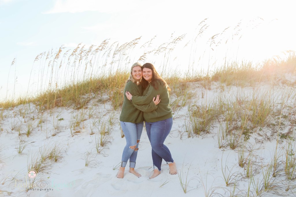 Sisters hugging each other with the sea oats behind them at Johnsons Beach in Perdido Key, Fl