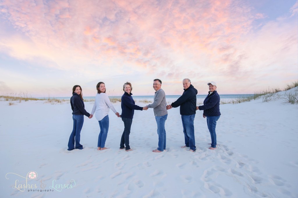 Family all holding hands and turning around to look at the camera at Johnsons Beach in Perdido Key, Fl