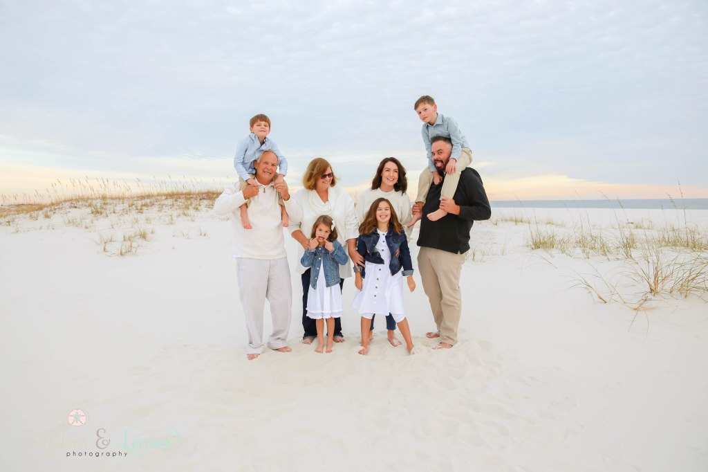 Picture of extended family all making silly faces with the water and sand dunes behind them at Johnsons Beach in Perdido Key, Fl