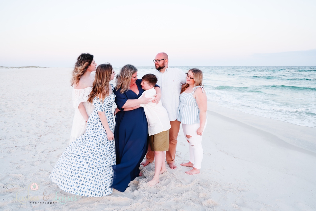 Family all hugging each other and standing next to the waters edge at Johnsons Beach in Perdido Key, Fl