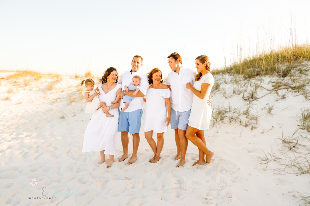 Grandma with her two adult children and their families with the sand dunes behind them at Johnsons Beach in Perdido Key, Fl