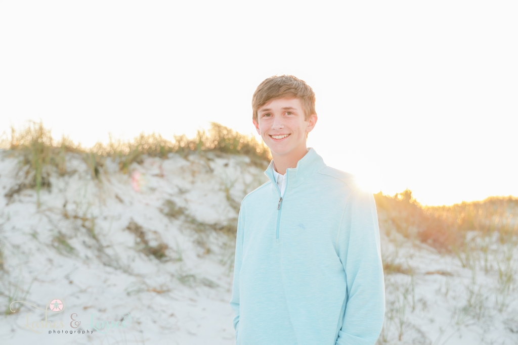 Close up photo of teen boy with the sunset and sand dunes behind him at Johnsons Beach in Perdido Key, Fl