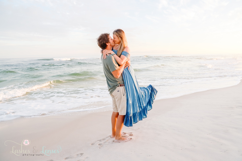 Husband lifting his wife and kissing her at the waters edge at Johnsons Beach in Perdido Key, Fl