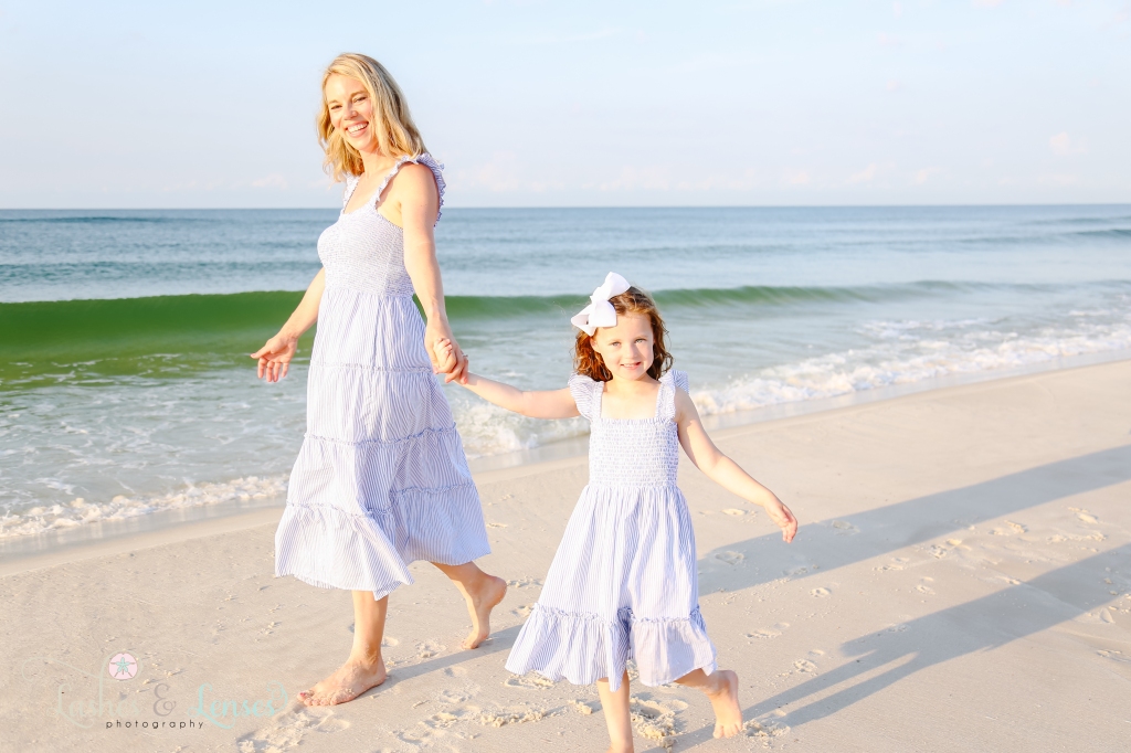 Mom and daughter walking along the edge of the water at Johnsons Beach in Perdido Key, Florida