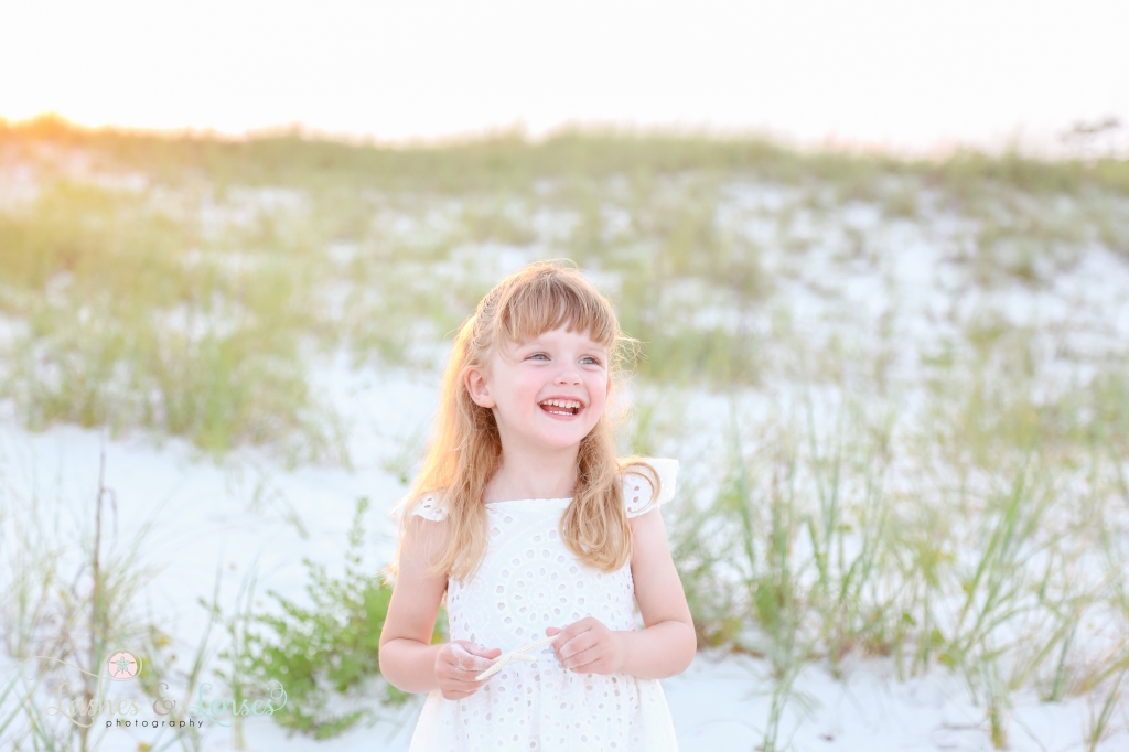 Close up photo of preschool age girl looking off towards ones side and laughing at Johnsons Beach in Perdido Key, Florida