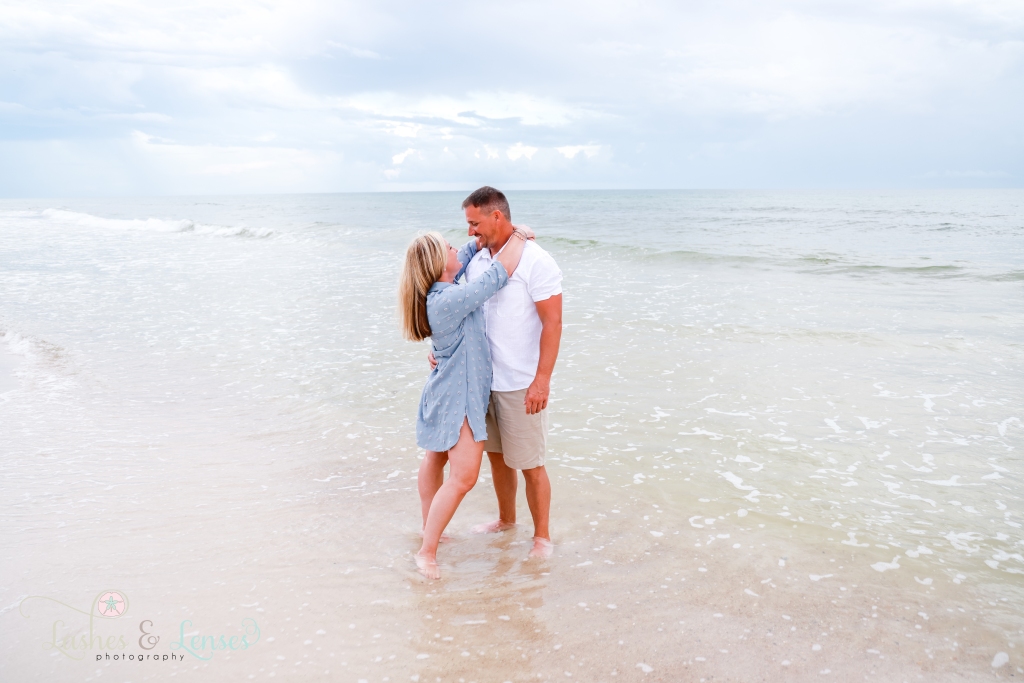 Husband and wife with their arms around each other and looking into each others eyes, they are standing in the water at Johnsons Beach in Perdido Key, Florida