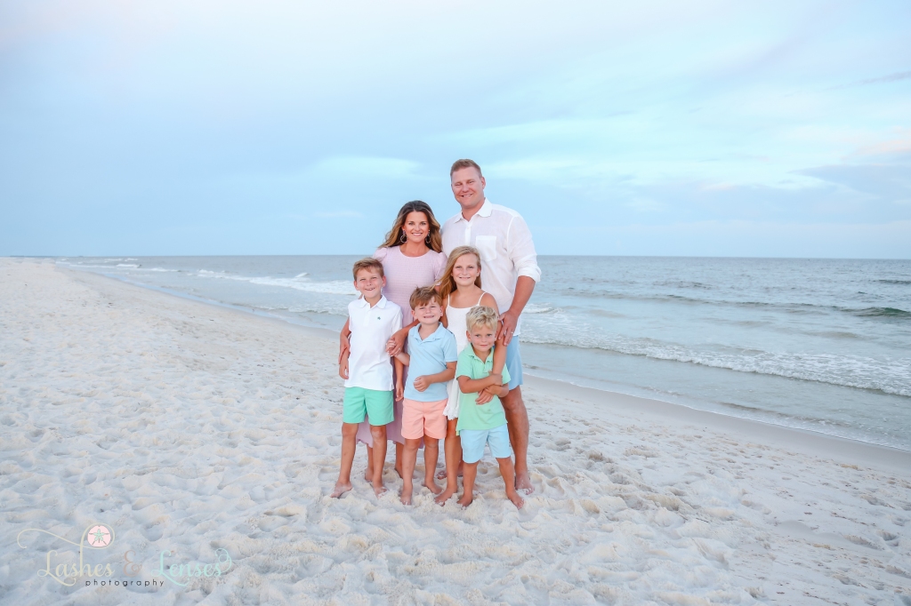 Mom, Dad and their four children standing on the beach close to the waters edge at Johnson's Beach in Perdido Key, Florida