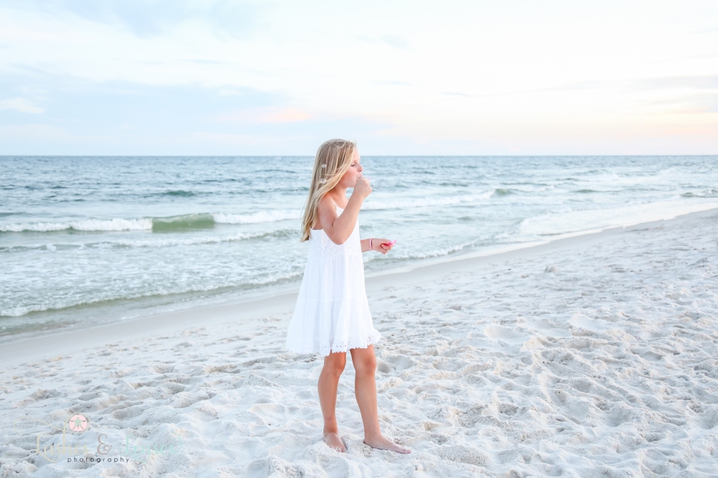 Little girl blowing bubbles while standing on the beach at Johnson's Beach in Perdido Key, Florida