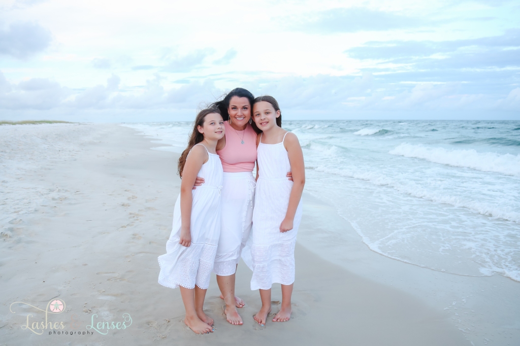 Mom and her two daughters standing at the edge of the water at Johnson's Beach in Perdido Key, Florida