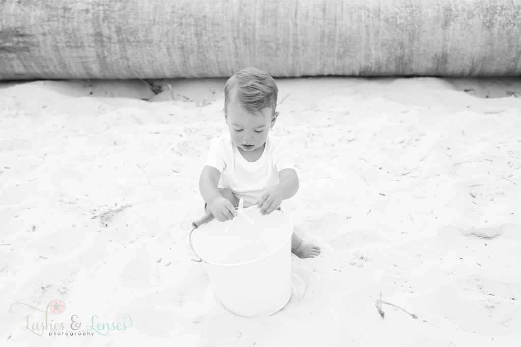 Black and White photo of toddler boy playing with a sand bucket at Johnson's Beach in Perdido Key, Florida