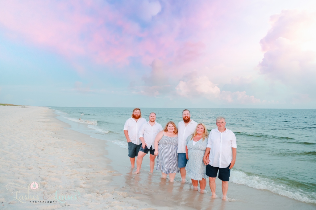 Family standing in the water with the waves rolling in behind them at Johnsons Beach in Perdido Key, Florida
