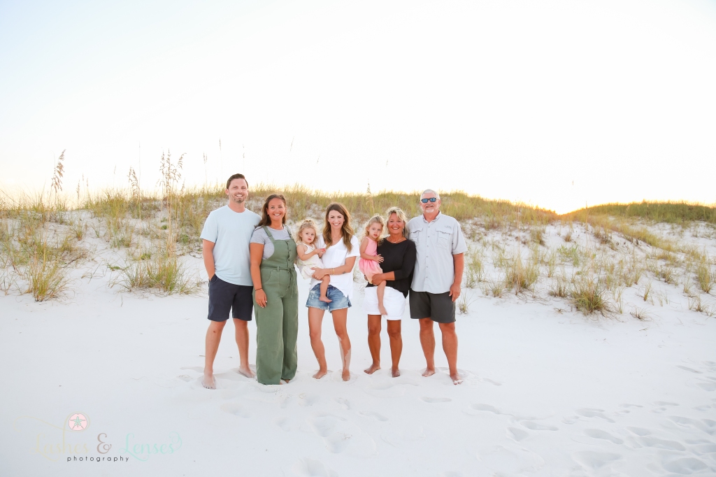 Extended family standing on the beach with large sand dunes behind them at Johnsons Beach in Perdido Key, Florida