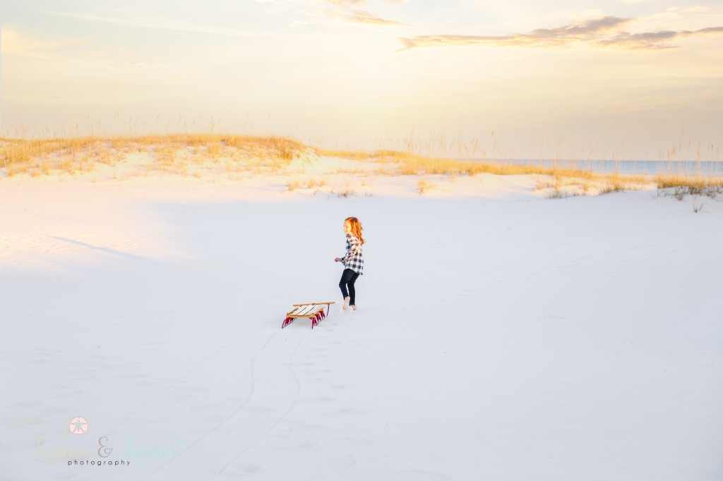 Little boy running with wood radio flyer sled in the sand at Johnsons Beach in Perdido Key, FL